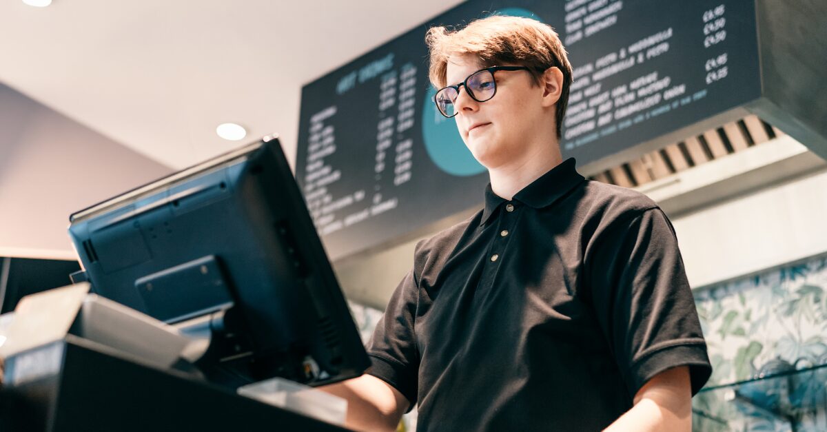 Photo of teenage boy operating a sales register at a restaurant.