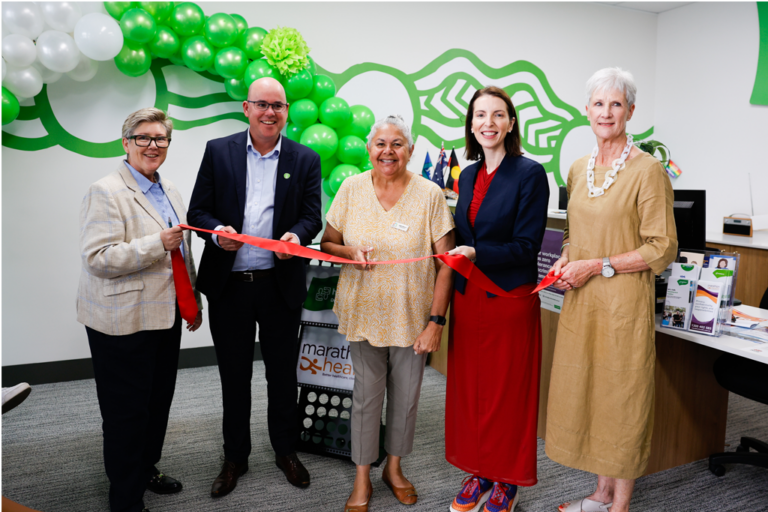 Five people stand together to cut ribbon at official opening.